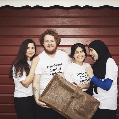 Fire KMAere med kuffert op ad rød væg